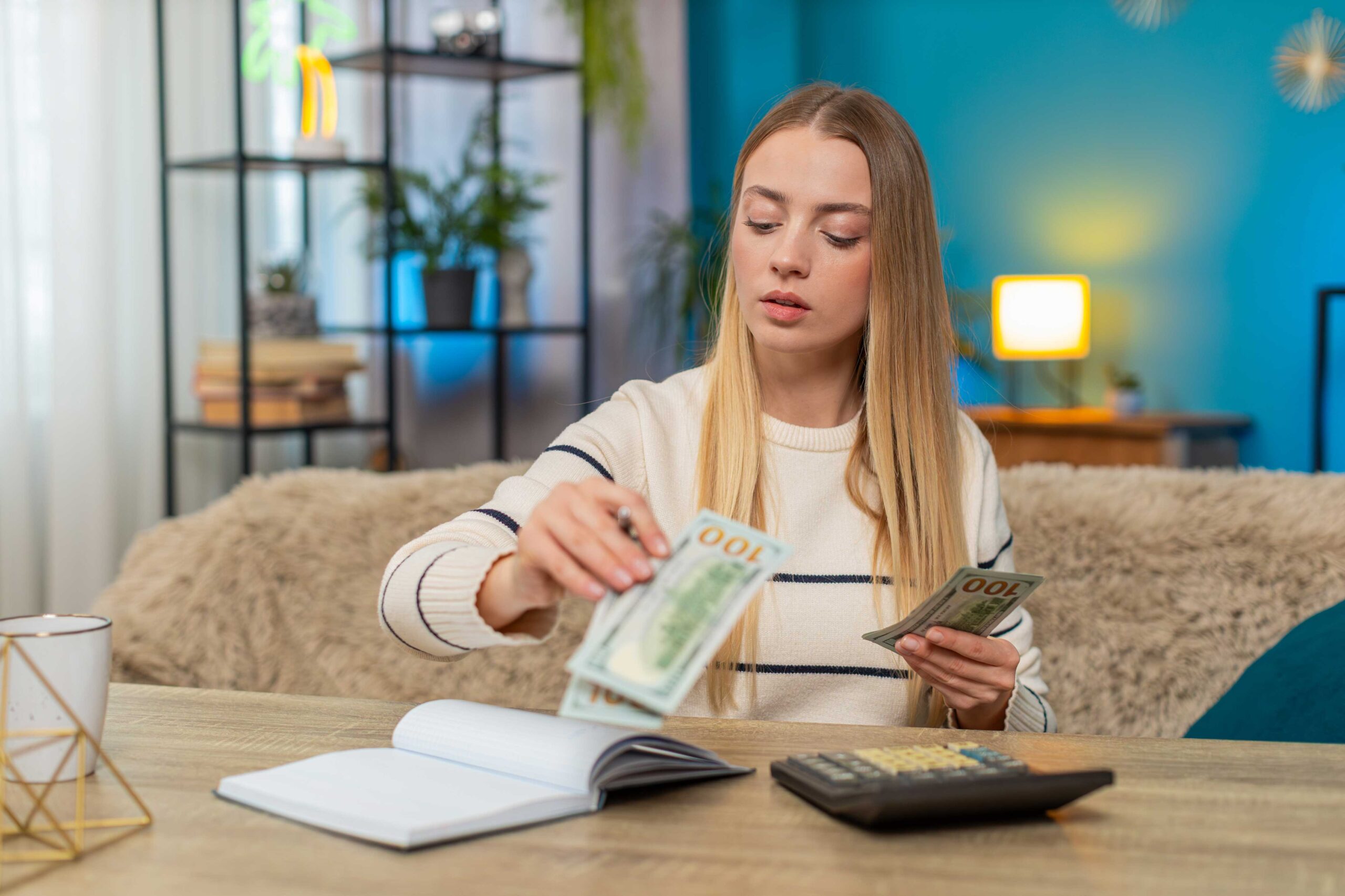 Jonge vrouw zit aan tafel en telt briefgeld